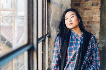 Woman leaning against brick wall by window - CUF47293