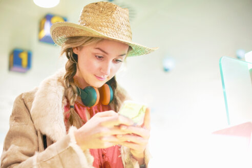 Junge Frau am Flughafen, mit Smartphone, Kopfhörer um den Hals - CUF47301