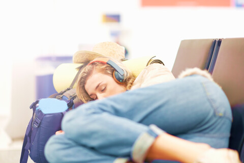 Young woman at airport, sleeping on seating in departure lounge stock photo