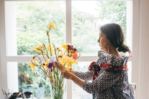 Frau arrangiert Blumen in einer Vase - CUF47309