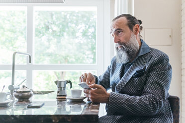 Man texting over coffee in kitchen - CUF47332