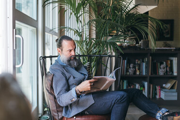 Man reading on armchair - CUF47336