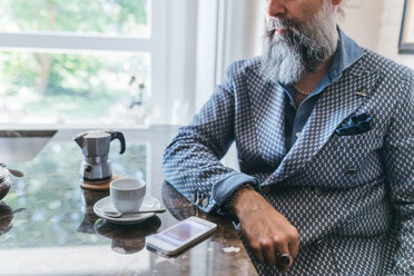 Man using cellphone over coffee in kitchen - CUF47348