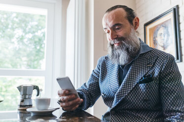 Man texting over coffee in kitchen - CUF47352