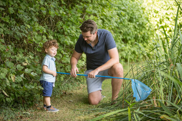 Vater und Kind mit Fischernetz im Park - CUF47421