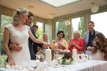 Brautpaar schneidet Hochzeitstorte beim Empfang an - CUF47483