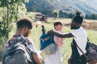 Drei junge erwachsene Wanderfreunde bereiten ihre Rucksäcke im Feld vor - CUF47495