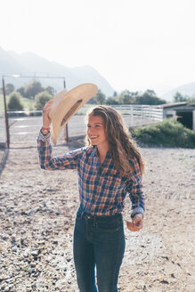 Cowgirl mit Stetson in einer ländlichen Reithalle - CUF47497