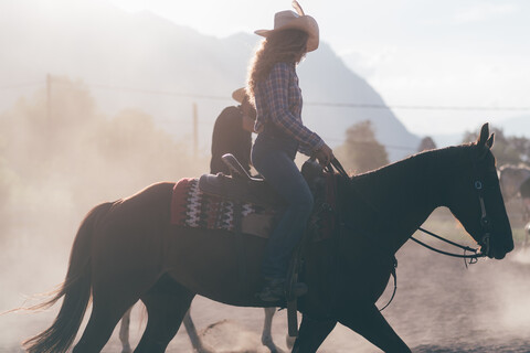 Cowgirl reitet auf einem staubigen Reitplatz, Seitenansicht Primaluna, Trentino-Südtirol, Italien, lizenzfreies Stockfoto