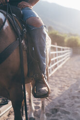 Man on horseback in rural equestrian arena, cropped - CUF47513