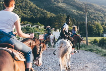 Erwachsene Freunde reiten auf Pferden auf einem ländlichen Feldweg, Rückansicht, Primaluna, Trentino-Südtirol, Italien - CUF47522