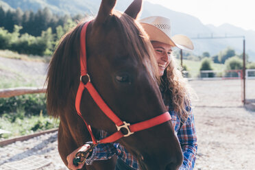 Junges Cowgirl führt Pferd in ländlicher Reithalle - CUF47532