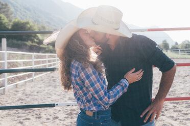 Junges Cowgirl und ihr Freund küssen sich in einer ländlichen Reitarena - CUF47539