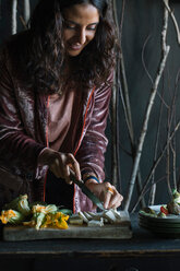 Young woman chopping fresh food on rustic cutting board - CUF47544