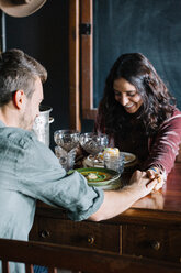 Romantisches junges Paar beim Essen, Händchenhalten am Tisch - CUF47552