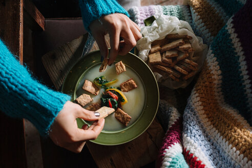 Junge Frau legt herzhafte Kekse in eine Schüssel mit frischen Lebensmitteln - CUF47571