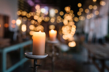 Close up of lit candle in cafe with decorative lights - CUF47586