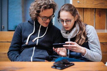 Ehepaar benutzt Smartphone in einem Café - CUF47629