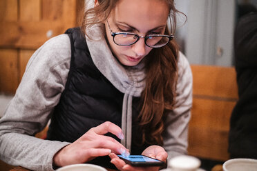 Junge Frau benutzt Smartphone in einem Cafe - CUF47632