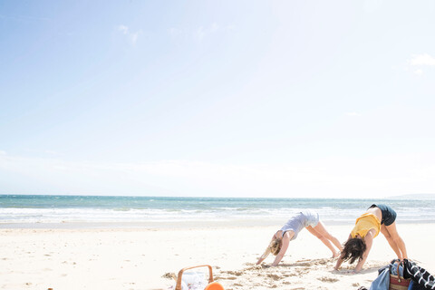 Schwestern genießen Yoga am Strand, lizenzfreies Stockfoto