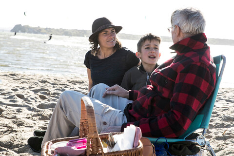 Älterer erwachsener Mann mit Tochter und Enkelkind am Strand, lizenzfreies Stockfoto