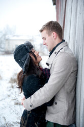 Junges Paar umarmt gegen Hütte im Schnee - CUF47820