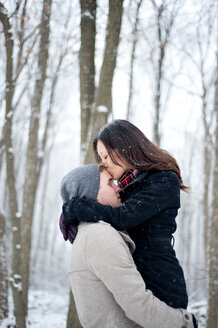 Romantische junge Frau küsst die Stirn ihres Freundes in einem verschneiten Wald, Ontario, Kanada - CUF47823