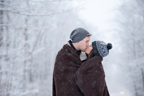 Romantisches junges Paar, das sich im verschneiten Wald küsst, Ontario, Kanada - CUF47827