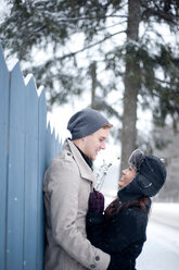 Junges Paar umarmt gegen Zaun im Schnee - CUF47829