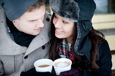 Young couple in winter hats having takeaway drinks - CUF47830