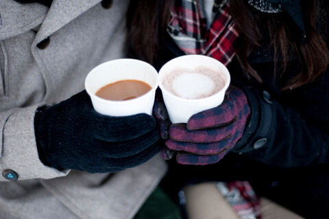 Young couple in winter gloves holding takeaway drinks, close up of hands stock photo