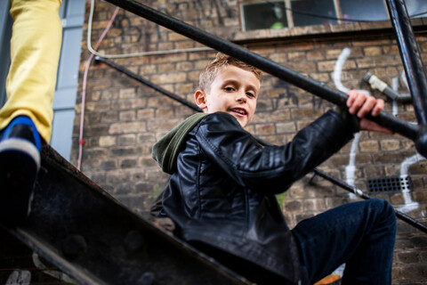 Junge sitzt auf Metalltreppe, lizenzfreies Stockfoto