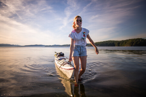 Young female kayaker pulling kayak, Quadra Island, Campbell River, Canada stock photo