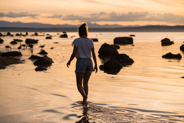 Junge Frau knöcheltief im Wasser bei Sonnenuntergang, Quadra Island, Campbell River, Kanada - CUF47861