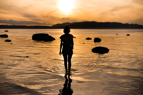 Junge Frau mit Blick auf den Sonnenuntergang, Silhouettenansicht von hinten, Quadra Island, Campbell River, Kanada, lizenzfreies Stockfoto