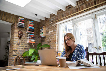 Pregnant mid adult woman typing on laptop at kitchen table - CUF47873