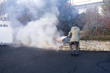 Man extinguishing cable fire in garden near the house - NDF00853