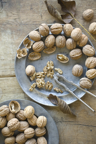 Whole and cracked organic walnuts and nutcracker on tin plates stock photo