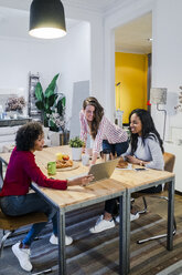 Three happy women with laptop at table - GIOF05480