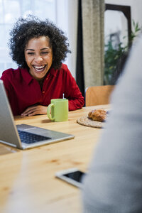 Lachende Frau mit Laptop am Tisch - GIOF05481