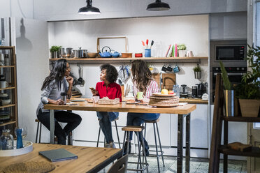 Drei Frauen unterhalten sich am Tisch in einem Loft - GIOF05485