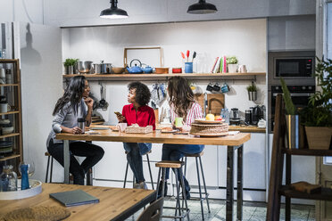 Three women talking at table in a loft - GIOF05485