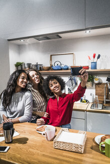 Drei glückliche Frauen posieren für ein Selfie am Tisch - GIOF05486