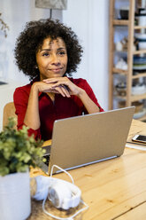 Smiling woman with laptop sitting at table - GIOF05496