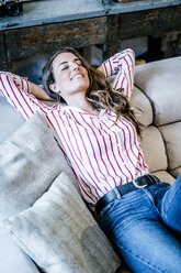 Smiling relaxed woman lying on couch - GIOF05517