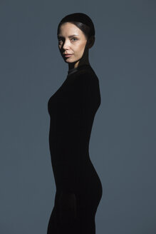 Porträt einer schlanken, schwarz gekleideten Frau mit Fackel im Gesicht - VGF00185