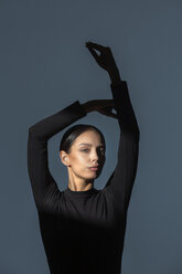 Portrait of woman dressed in black with flare on her face doing stretching exercise - VGF00191