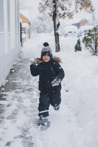 Portrait of smiling toddler throwing snowball stock photo