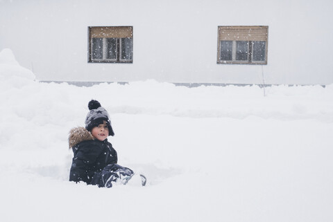 Porträt eines Kleinkindes im Schnee sitzend, lizenzfreies Stockfoto