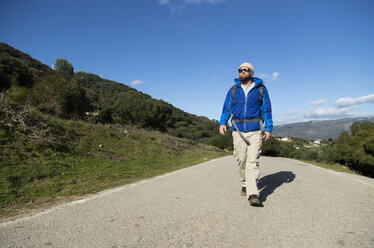 Spanien, Andalusien, Tarifa, Mann auf Wanderschaft, der auf der Straße läuft - KBF00411